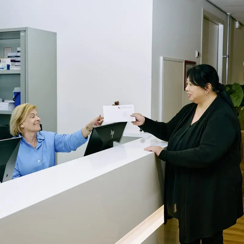 Een bezoeker ontvangt een envelop aan de balie van het Bariatrisch Centrum